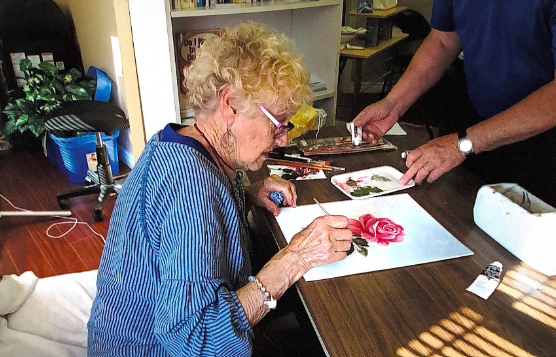 A woman working on a painting of a flower